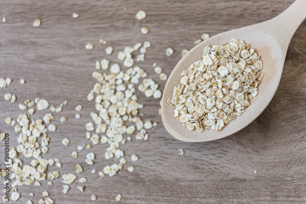 Oatmeal in a wooden spoon on the kitchen counter in brown wooden colour. Selected focus. Healthy food concept. Oatmeal in a wooden spoon on the kitchen counter in brown wooden colour. Selected focus. Healthy food concept.