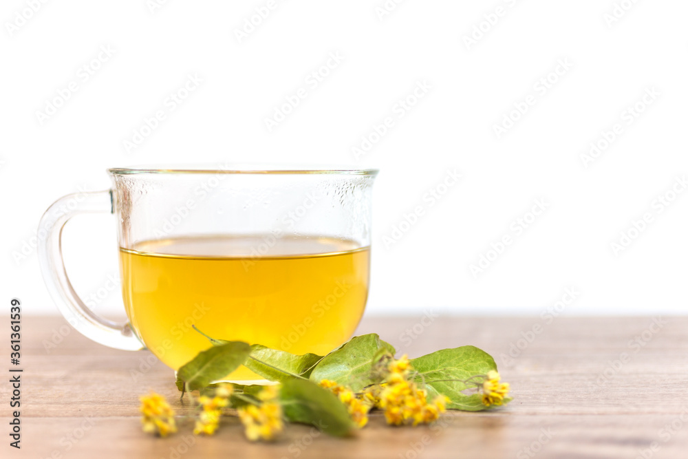 Glass cup of tea on a wooden table with dried linden. Selected focus.