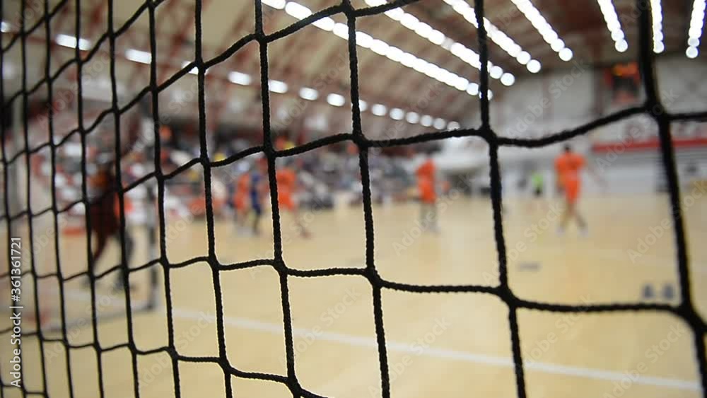 Handball match scene with goalpost and goalkeeper and players attacking in the background