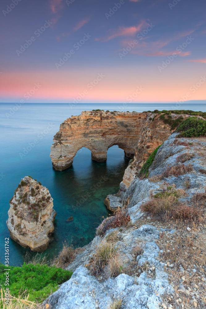 Algarve in Portugal and its amazing beaches, is a summer holiday destination for many tourists in Europe. Landscape with cliffs on the coast at colorful sunset. Pure nature, blue sea, sand.
