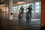 Two fit young men exercising together on stationary bikes