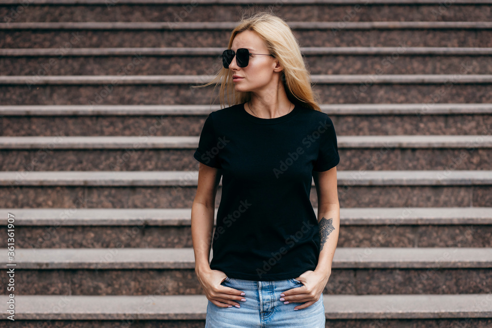 Stylish blonde girl wearing black t-shirt and glasses posing against street  , urban clothing style. Street photography Stock Photo | Adobe Stock