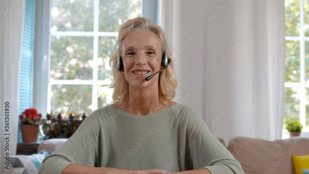 Senior woman in headset talking to client online at home office Senior woman in headset talking to client online at home office