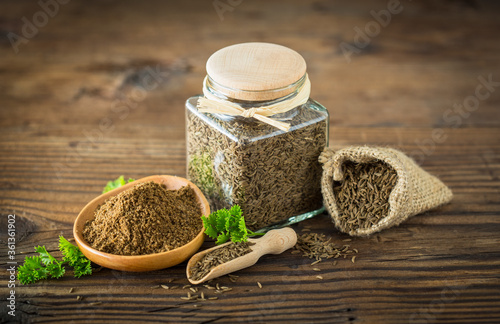 Fresh cumin seeds and powder on the wooden table photo