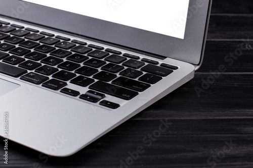 Close up silver laptop with black keyboard. Dark wooden background.
