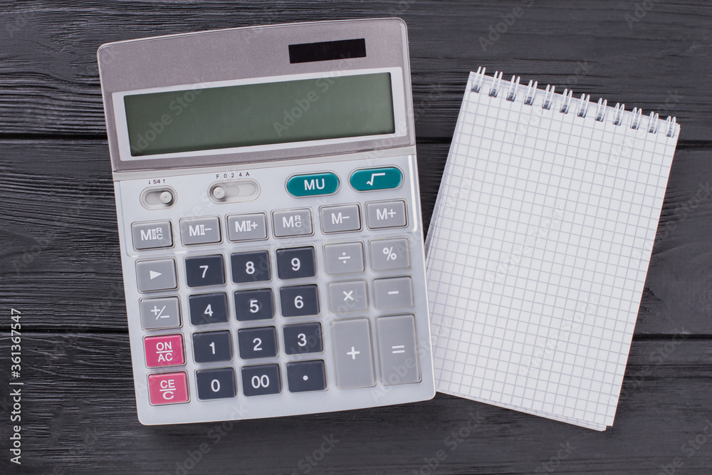 Calculator and notepad on dark wooden table. Top view flat lay. Calculator and notepad on dark wooden table. Top view flat lay.