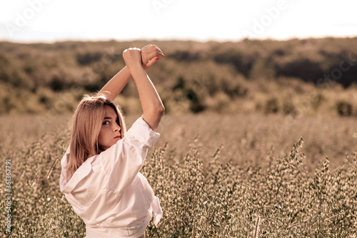 Young busty girl in a white dress on an oat field. photo