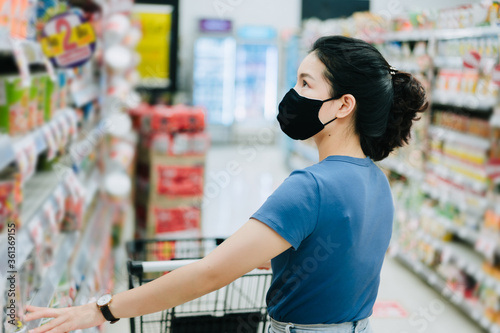 Young Asian woman wear a black face mask are shopping in supermarket