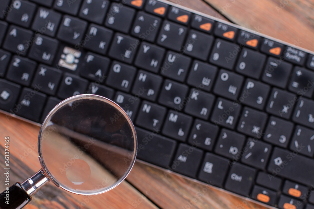 Fototapeta premium Magnifying glass over black keyboard. Missing key in the keyboard.