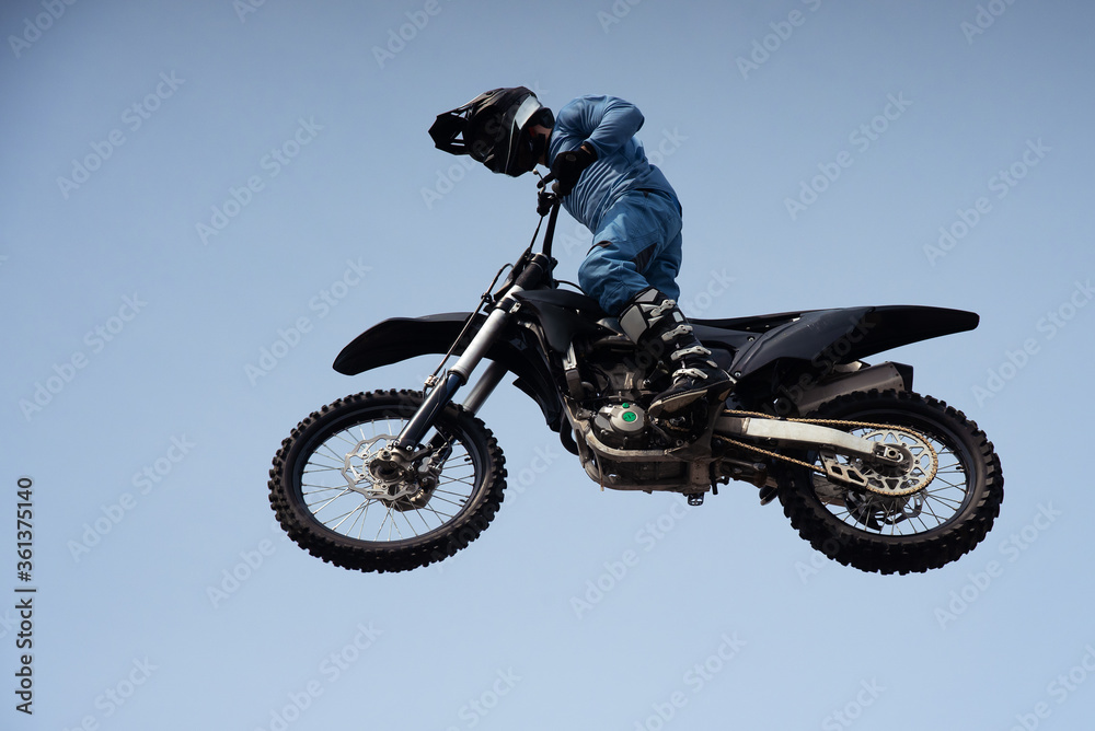 rider in a helmet makes a risky jump in the air on a black motorcycle rider in a helmet makes a risky jump in the air on a black motorcycle