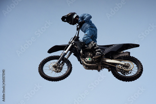 rider in a helmet makes a risky jump in the air on a black motorcycle