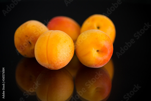small handful of ripe apricots on black background photo