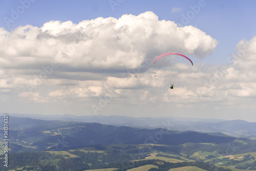 Paraglider soars in the sky against the background of blue mountains