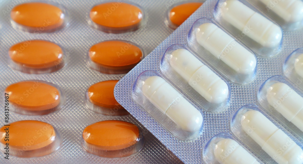 Medicines orange oval pills and white capsules in a blister close-up Medicines orange oval pills and white capsules in a blister close-up
