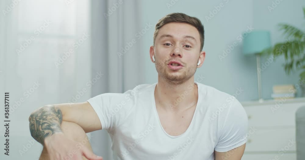 Close up portrait of a young athlete speaking on camera. A sporty guy carying out online fitness training at home. Video lessons on workout, gymnastics, aerobics. Healthy and Wealthy lisfestyle.
