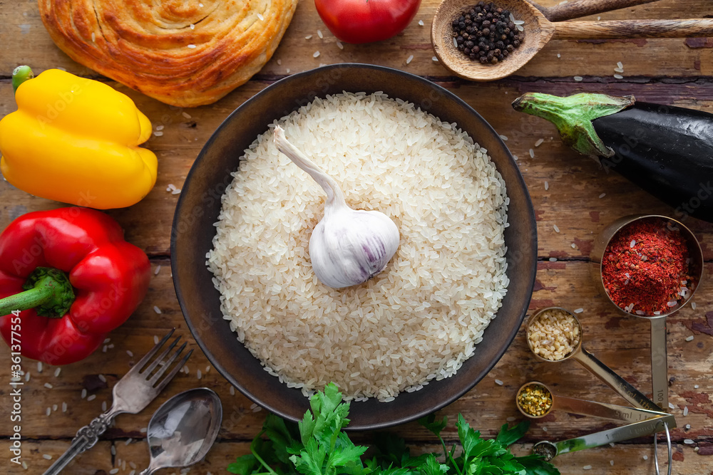 Pilaf ingredients, rice, vegetables, pita, cutlery, spices on rustic background Pilaf ingredients, rice, vegetables, pita, cutlery, spices on rustic background