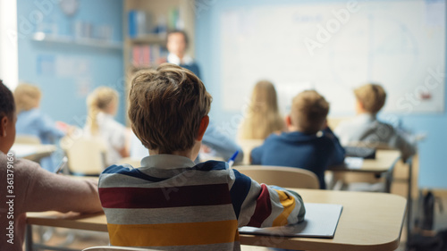 Caring Teacher Explains Lesson to a Classroom Full of Bright Diverse Children. In Elementary School with Group of Smart Multiethnic Kids Learning Science.