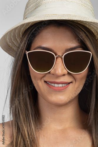 detail a portrait of a latin woman smiling with sunglasses and a straw hat, studio 