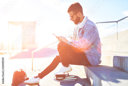 Young man tourist searching sightseeng information on web page via modern digital tablet using internet connection during his trip. Hipster guy sitting with touch pad outdoors photo