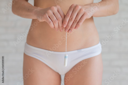 Photography A faceless woman in white panties holds a tampon during a regular menstrual cycle