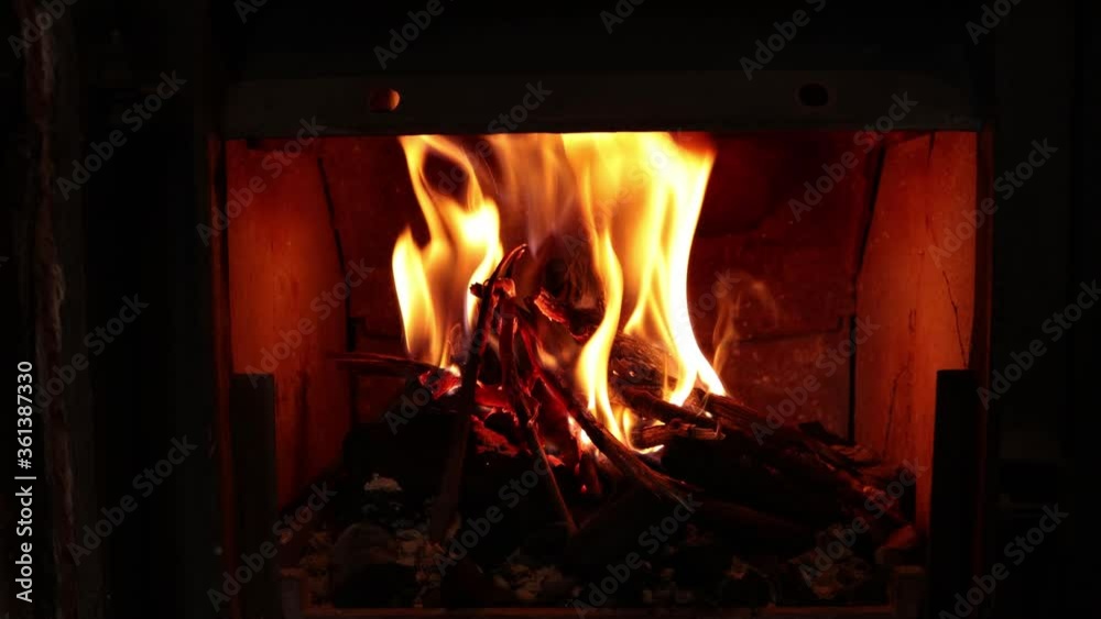A wooden fire burning in a small fireplace with big flames and sparks. 4k shot. A wooden fire burning in a small fireplace with big flames and sparks. 4k shot.