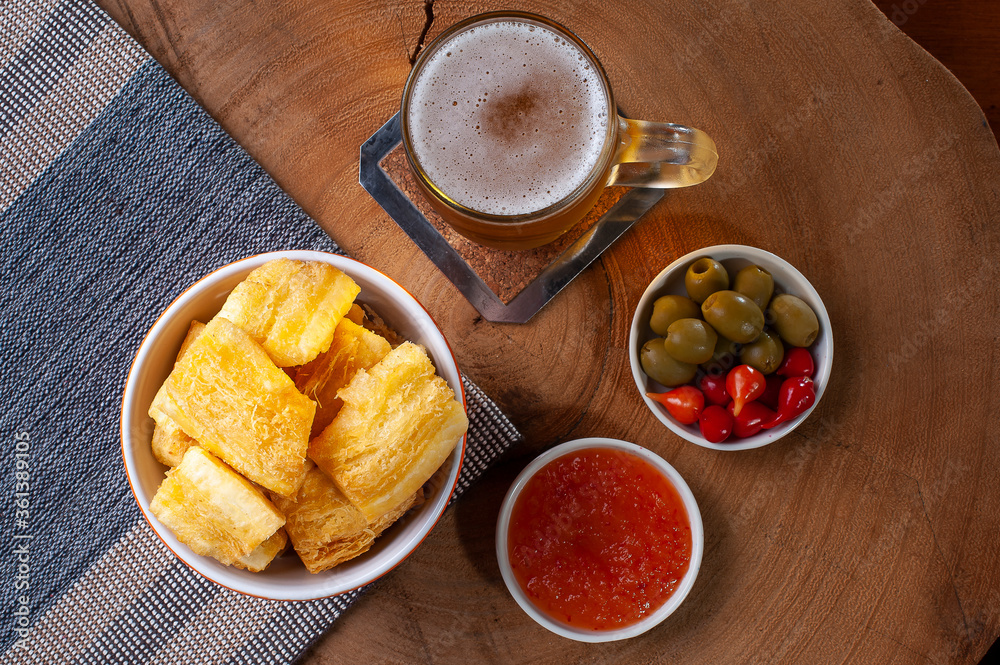 .Fried manioc. Traditional Brazilian food dish. Accompanied by pepper jam, olives and pepper pout. Glass of beer. Top view .Fried manioc. Traditional Brazilian food dish. Accompanied by pepper jam, olives and pepper pout. Glass of beer. Top view