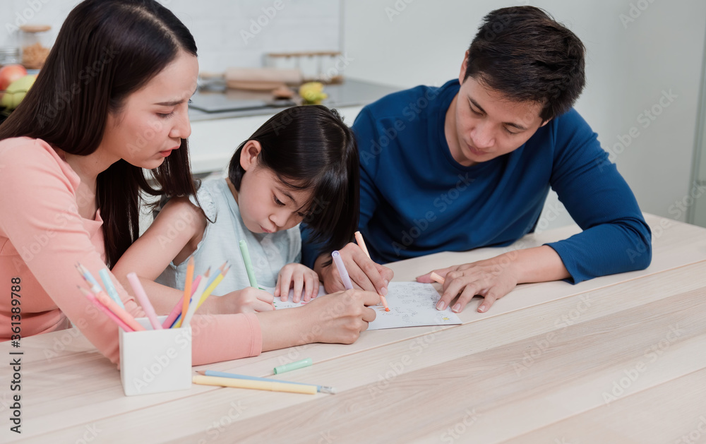 Asian women and men teaching girls to write and draw on paper. Three people had a happy facial expression at home It is a new way of life for the family. Asian women and men teaching girls to write and draw on paper. Three people had a happy facial expression at home It is a new way of life for the family.