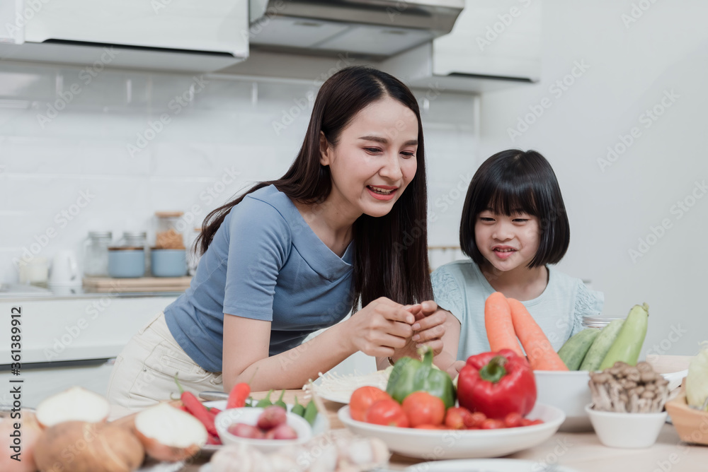 Beautiful woman And two lovely Asian girls are teaching cooking in the kitchen at home. Two people are happy. It's a new normal way of life. Beautiful woman And two lovely Asian girls are teaching cooking in the kitchen at home. Two people are happy. It's a new normal way of life.