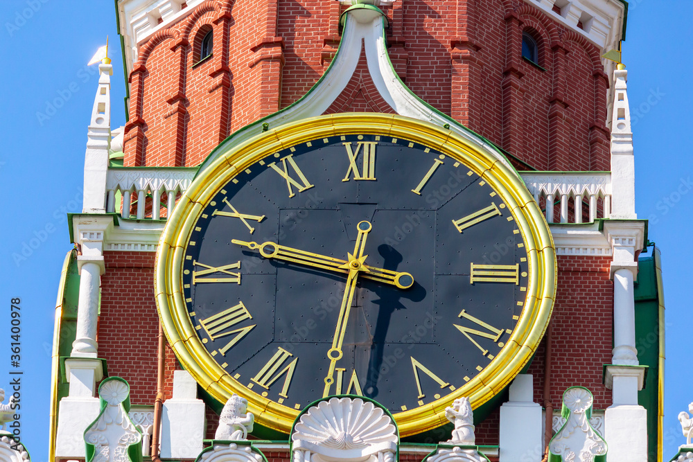 Close up view of large clock on Spasskaya Tower of Moscow Kremlin on a summer morning. Blue sky in the background. Theme of travel in Russia.