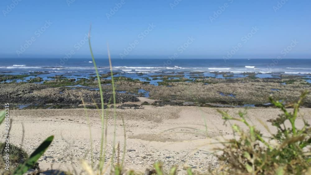Sea, beach boulders, pebble shore and waves. Sea waves breaking on rocks. Sunny beach with sand dunes and blue sky in Esposende, Portugal. Sea, beach boulders, pebble shore and waves. Sea waves breaking on rocks. Sunny beach with sand dunes and blue sky in Esposende, Portugal.