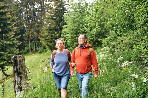 Middle age couple hiking in green forest, active family time