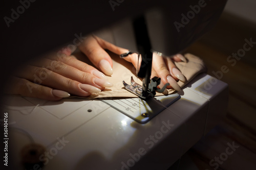 The woman is sewing with sewing machine. Sewing is the craft of fastening or attaching objects using stitches made with a needle and thread. Sewing is one of the oldest of the textile arts.