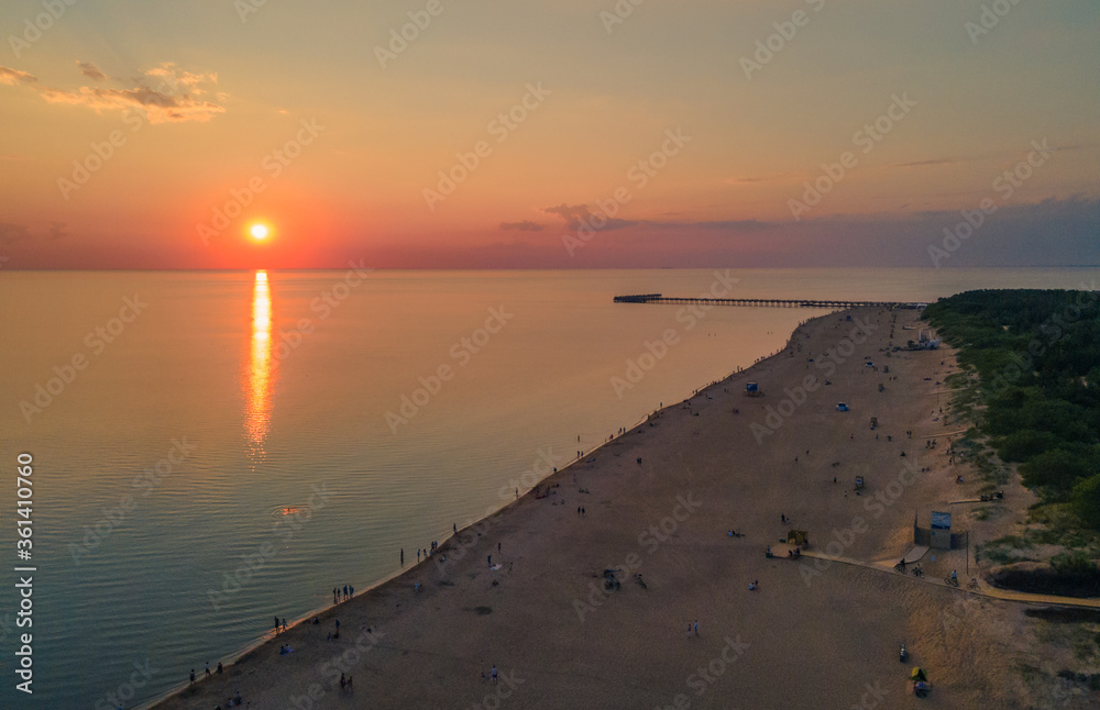 Fototapeta premium Aerial view of sunset over the sea in Palanga, Lithuania. Sandy coastline with the bridge to the sea.