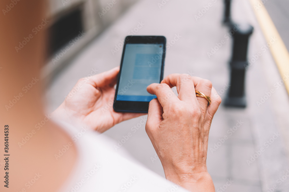 Cropped image of woman's hands holding mobile phone with copy space area for your text message or advertising content, female tourist using cell telephone for navigation while walking on the street