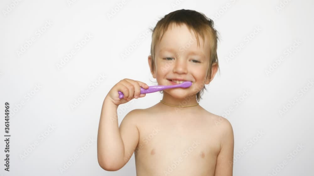 A beautiful little boy brushes his teeth laughing hard against white background A beautiful little boy brushes his teeth laughing hard against white background