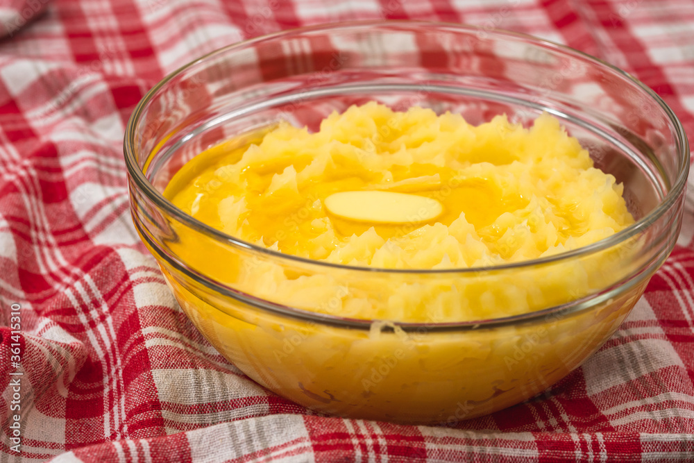 Mushed potato with melting butter close up in a glass bowl on kitchen table