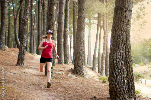 Woman with a cap running through a forest, enjoying nature