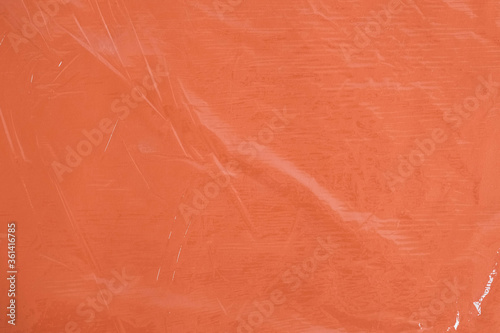 Wrinkled transparent plastic texture on an orange background. Transparent cellophane texture on an orange backing. Top view. Copy, empty space for text