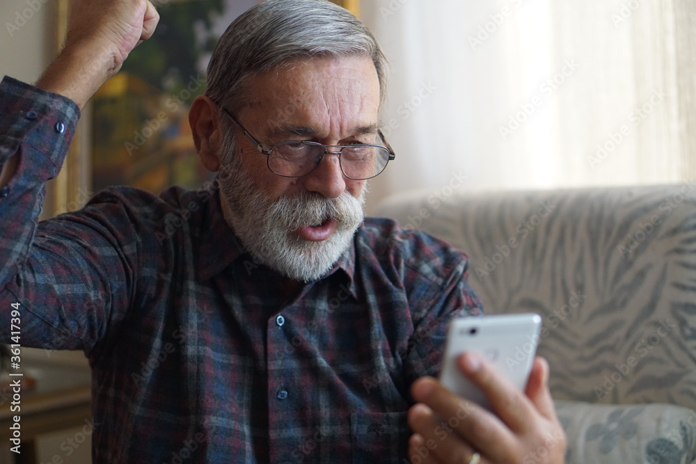 Excited senior man looking at his smartphone. Excited senior man looking at his smartphone.