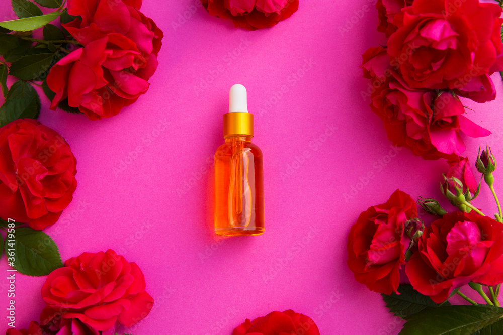 cosmetic glass bottle for essential oils withrose flowerson a pink background. Spa still life with Natural Serums in glass bottle. Dropper Bottle Mock-Up cosmetic glass bottle for essential oils withrose flowerson a pink background. Spa still life with Natural Serums in glass bottle. Dropper Bottle Mock-Up