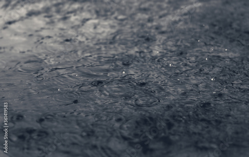 Rain drops on the surface of water during hard rain fall at night.
