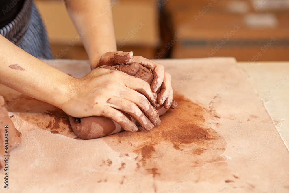 hands of a potter at work with clay in an art studio