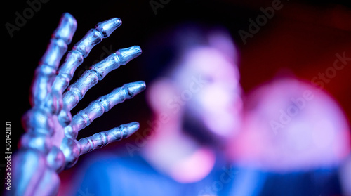 Obraz na plátně the hand of the skeleton in the foreground in the nightclub blurred man in the b