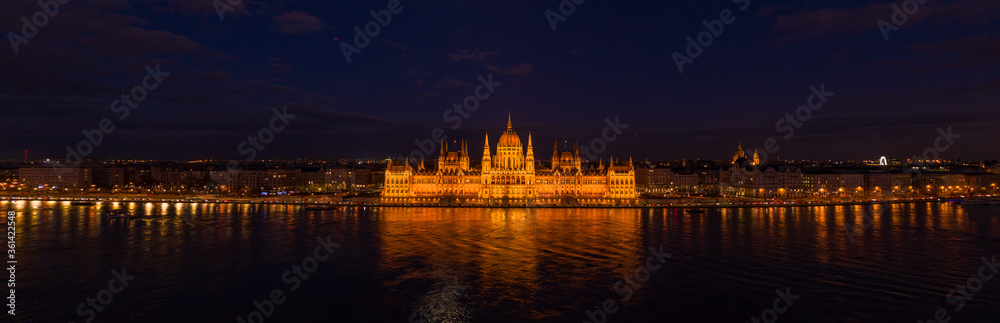 Panoramic aerial drone shot of Hungarian Parliament with lights on during Budapest evening