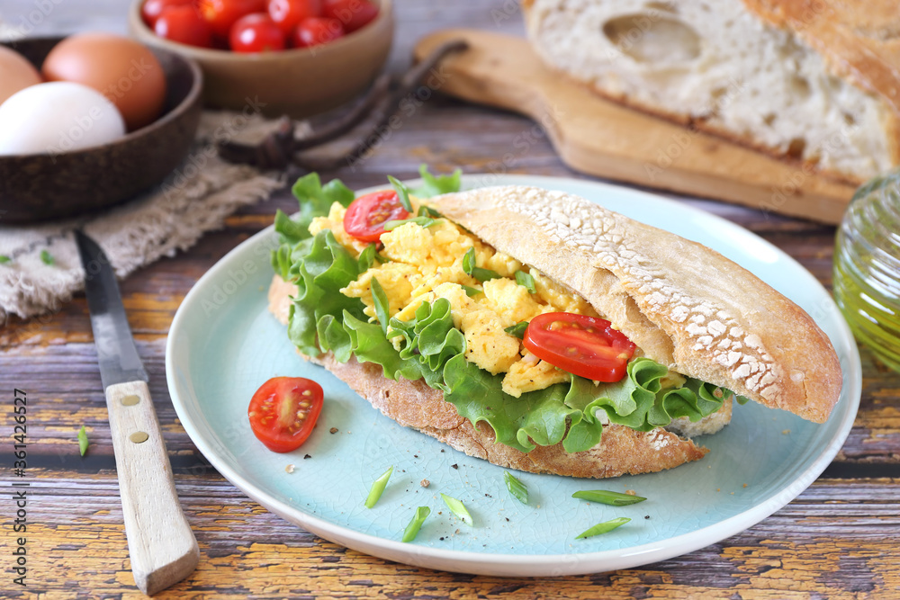 Tasty and hearty breakfast.Sandwich with scrambled eggs, lettuce and cherry tomatoes