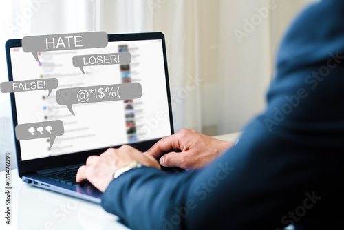 Hate Speech concept. a man works at a laptop and receives messages with notification icons of bullying on social networks and hatred on the Internet