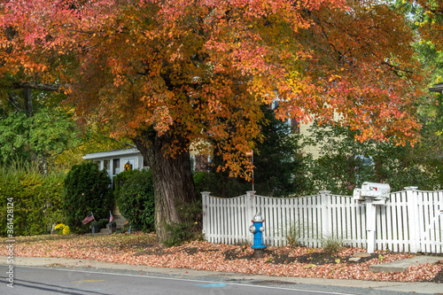 Quaint New England village scene with white picket fence and fall foliage