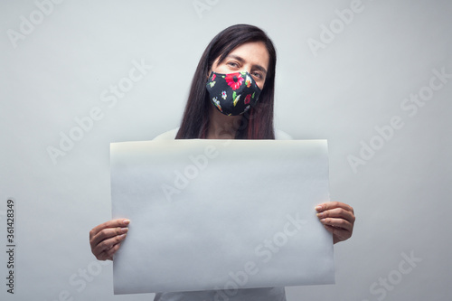 Woman portrait in inspirational mood with face mask and white sign, physycal distancing. photo