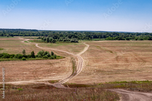 A dirt road passing through a field in a picturesque location.