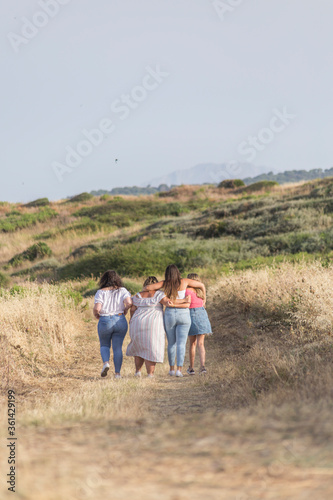 group of friends walks embracing on a meadow